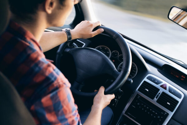 Young driver in his shirt in a nice modern car in motion
